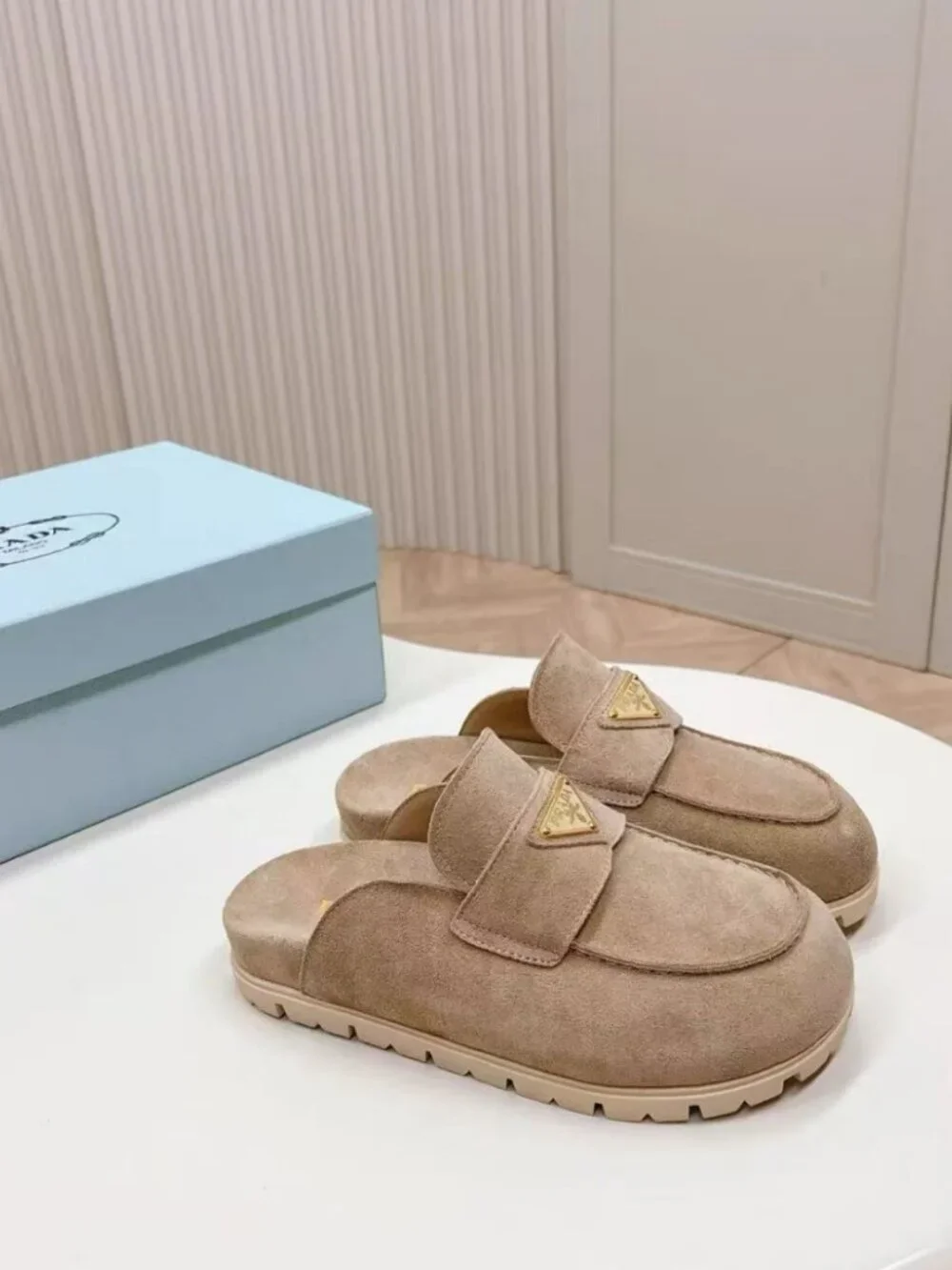 Prada beige slip‑on mules with triangular logo badge